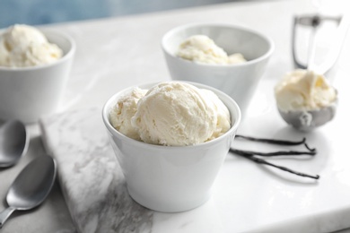 Bowls with tasty vanilla ice cream on marble board
