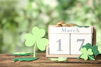 Photo of Composition with block calendar on wooden table against blurred greenery. St. Patrick's Day celebration