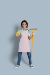 Photo of African American woman with yellow broom on grey background