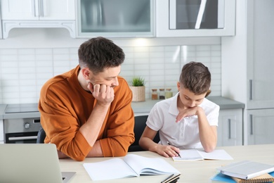 Dad helping his son with difficult homework assignment in kitchen
