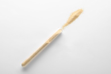 Glass tube with garlic powder on white background, top view