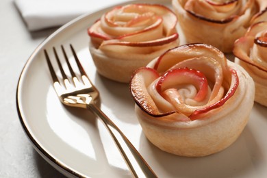 Freshly baked apple roses served on light table, closeup. Beautiful dessert