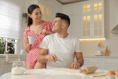 Photo of Happy couple wearing pyjamas and cooking together in kitchen