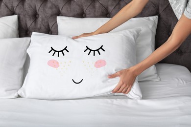Woman plumping pillow with cute face in bedroom, closeup