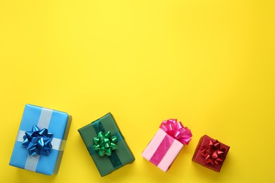 Many colorful gift boxes on yellow background, flat lay. Space for text
