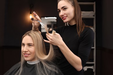 Professional hairdresser cutting woman's hair in salon
