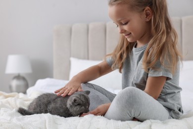 Cute little girl with kitten on bed at home. Childhood pet
