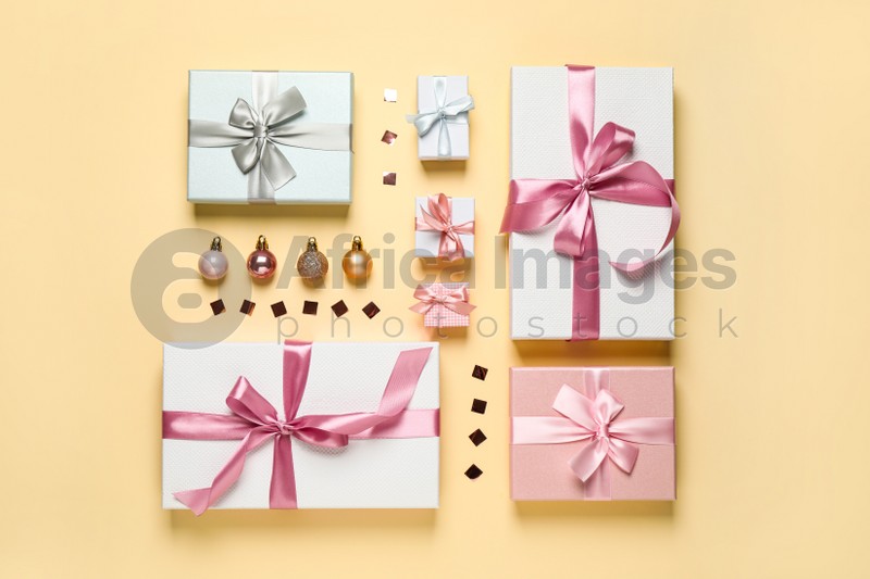 Beautiful gift boxes, Christmas balls and confetti on beige background, flat lay