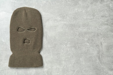 Photo of Beige knitted balaclava on grey table, top view. Space for text