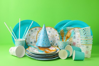 Set of disposable tableware on green background