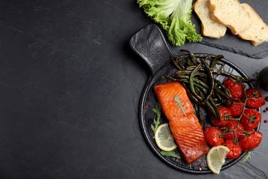Photo of Delicious cooked salmon and vegetables served on black table, flat lay with space for text. Healthy meals from air fryer