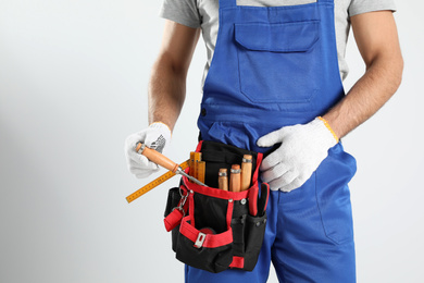 Photo of Carpenter with tool belt on light background, closeup