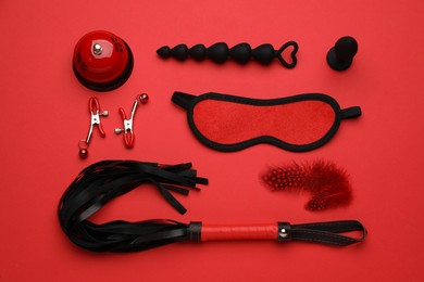 Photo of Sex toys and accessories on red background, flat lay