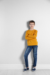Cute little boy posing near light wall