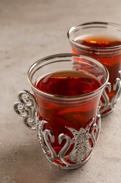Glasses of traditional Turkish tea in vintage holders on light grey table, closeup