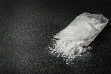 Cocaine in plastic bag on dark background, closeup. Space for text