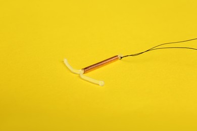 T-shaped intrauterine birth control device on yellow background