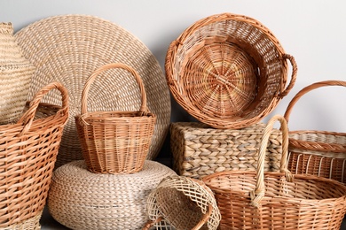 Many different wicker baskets made of natural material on light background, closeup
