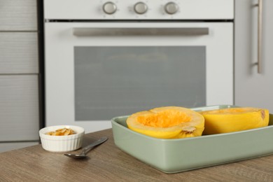 Halves of fresh spaghetti squash in baking dish on wooden table indoors, space for text