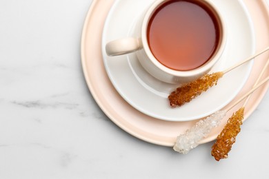 Sticks with sugar crystals served to tea on white marble table, top view. Space for text