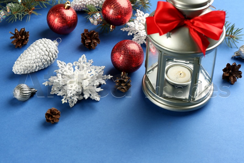Photo of Christmas lantern with burning candle and festive decor on blue background