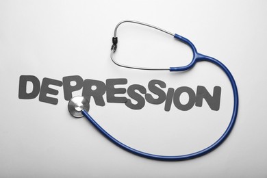 Word Depression and stethoscope on white background, flat lay