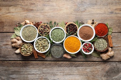 Flat lay composition with different natural spices and herbs on wooden table