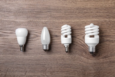 New fluorescent lamp bulbs on wooden background, flat lay