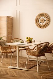 Stylish white dining table and wicker chairs in room. Interior design