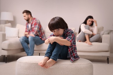 Sad little boy and his arguing parents on sofa in living room