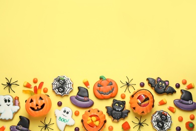 Tasty cookies and sweets for Halloween party on yellow background, flat lay. Space for text