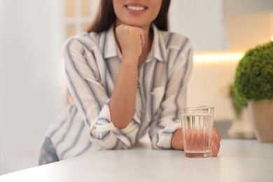 Young woman with glass of pure water at countertop in kitchen, closeup