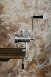 Photo of Metal manual meat grinder on wooden table against color background