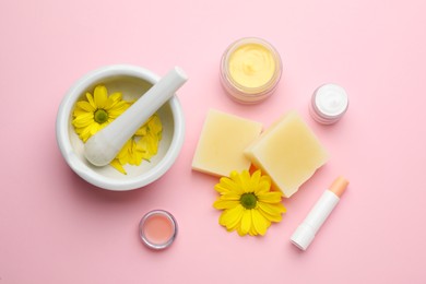 Flat lay composition with beeswax and cosmetic products on pink background