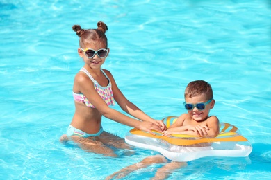 Cute little children with inflatable ring in swimming pool