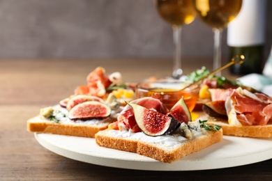 Photo of Sandwiches with figs, proscuitto and cheese on wooden table, closeup