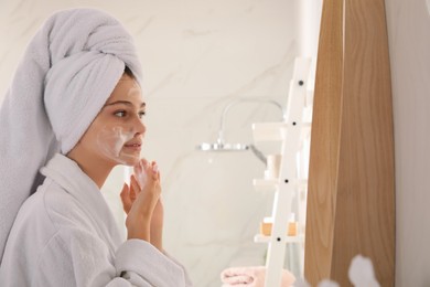 Beautiful teenage girl applying cleansing foam onto face in bathroom. Skin care cosmetic