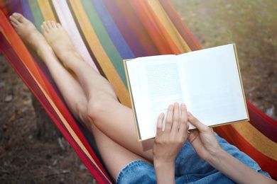 Woman with book relaxing in hammock outdoors on summer day, closeup