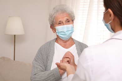 Doctor taking care of senior woman with protective mask at nursing home