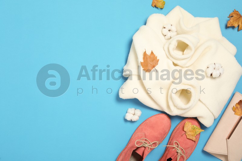 Photo of Flat lay composition with sweater and dry leaves on light blue background, space for text. Autumn season