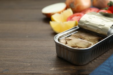 Photo of Open tin can of tasty cod liver on wooden table, closeup. Space for text