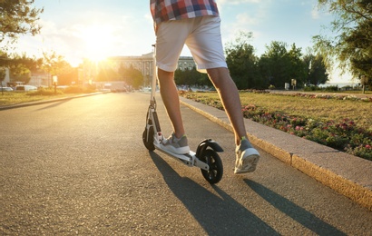 Man riding modern kick scooter in park, closeup