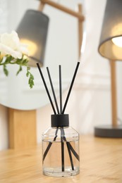 Photo of Aromatic reed air freshener on wooden table in room