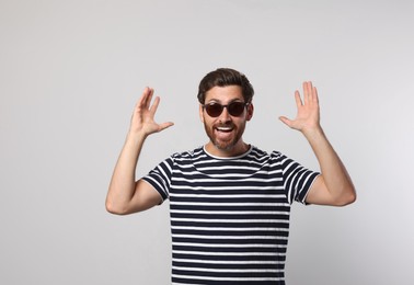 Portrait of excited bearded man with stylish sunglasses on grey background