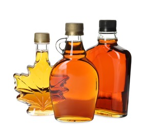 Different bottles of tasty maple syrup on white background