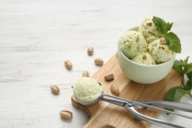 Tasty pistachio ice cream served on white wooden table, space for text