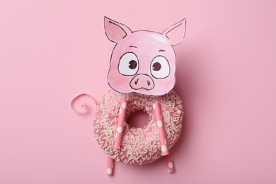 Funny pig made with donut and piece of paper on pink background, top view
