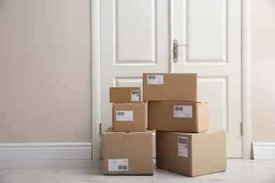 Stacked parcels near door on floor, space for text. Delivery service