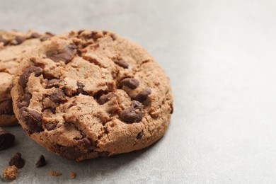 Photo of Delicious chocolate chip cookies on grey table, closeup. Space for text