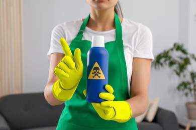 Photo of Woman showing bottle of toxic household chemical with warning sign, closeup